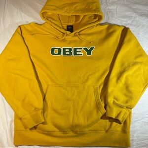 Yellow Obey Propaganda hoodie with green text on front